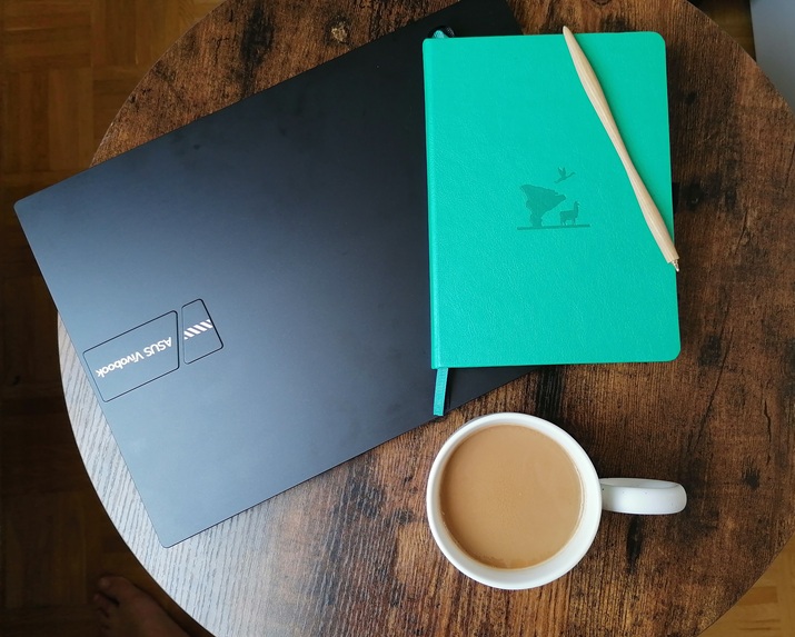 Tisch mit Kaffee, Laptop und Notizbuch